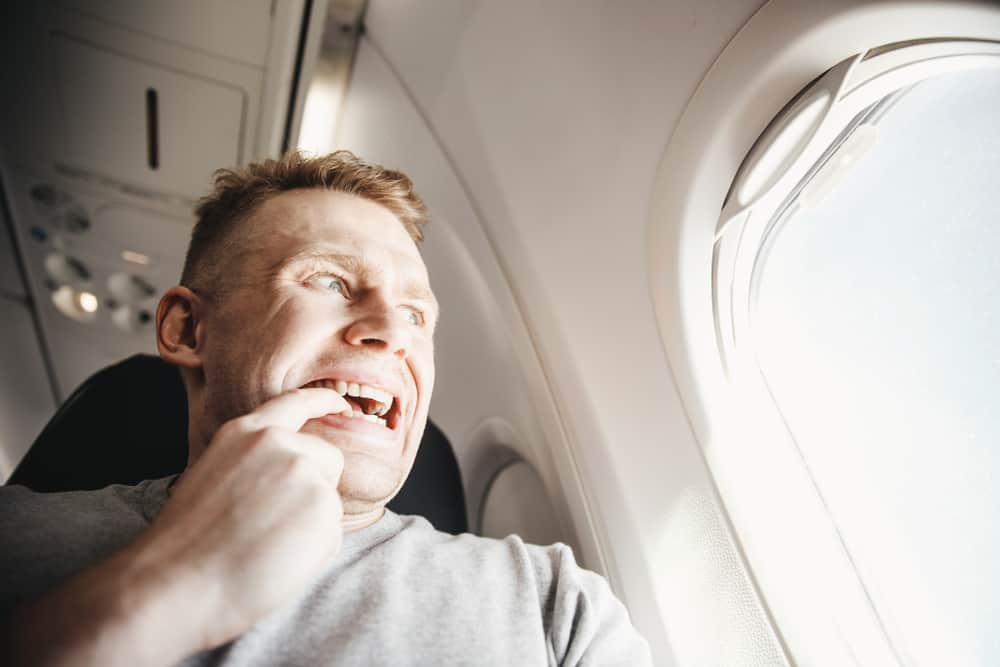 Mand der sidder i en flyvemaskine.. En finger i munden og anstrengt ansigtsudtryk, fordi han har flyskræk.