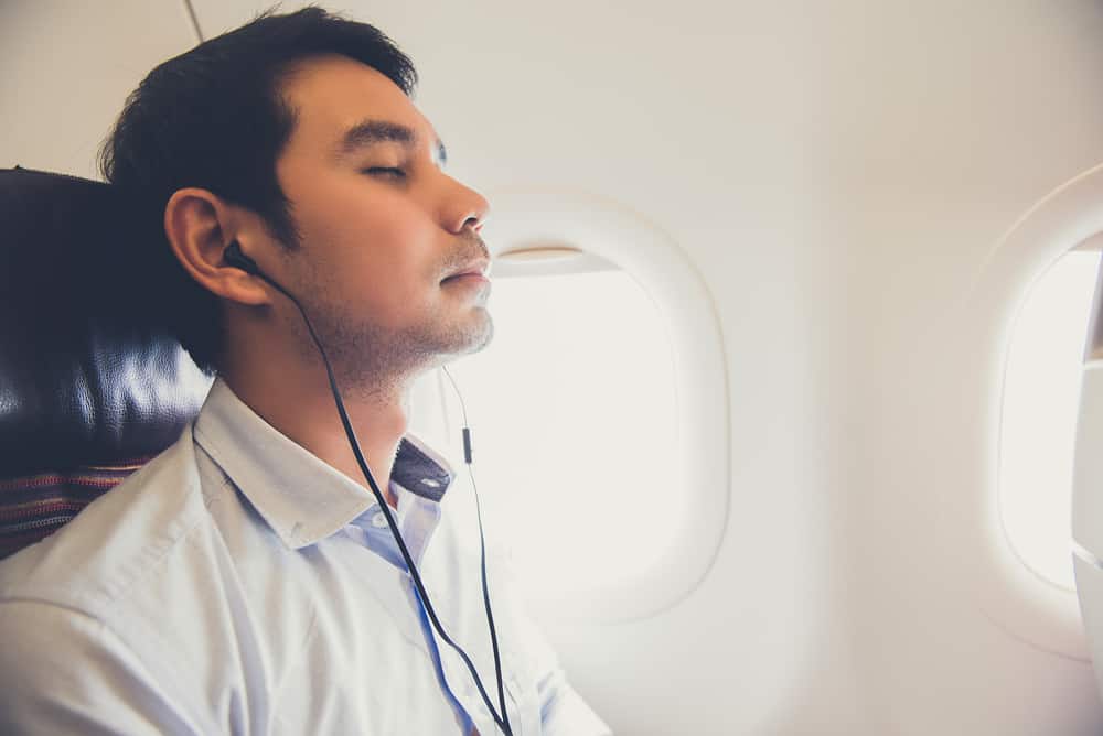 Mand på flyvemaskine med høretelefoner i ørerne.